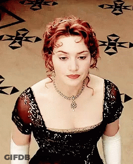 A Woman Wearing A Black Dress And White Gloves Is Looking Down GIF
