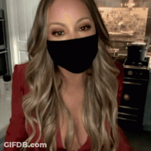 A Woman Wearing A Black Face Mask Is Sitting In A Kitchen GIF
