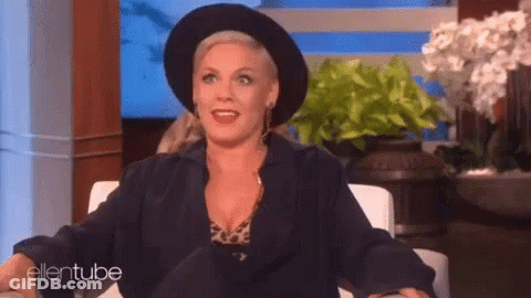 A Woman Wearing A Black Hat And A Black Jacket Is Sitting In A Chair On A Show . GIF