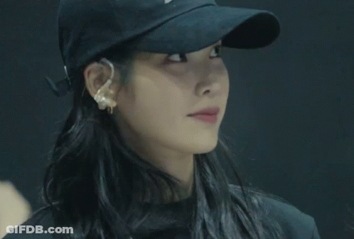 A Woman Wearing A Black Hat And Earrings Is Crossing Her Arms GIF