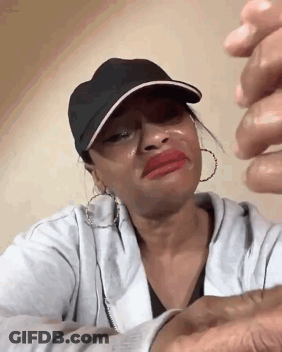 A Woman Wearing A Black Hat And Earrings Is Crying GIF