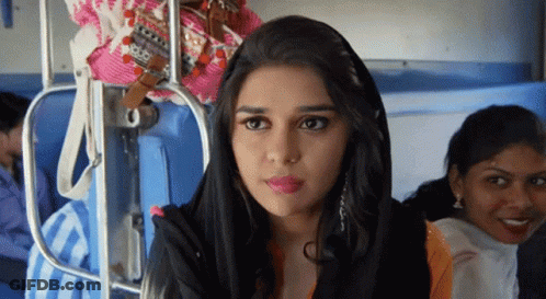 A Woman Wearing A Black Head Scarf Is Sitting On A Train GIF