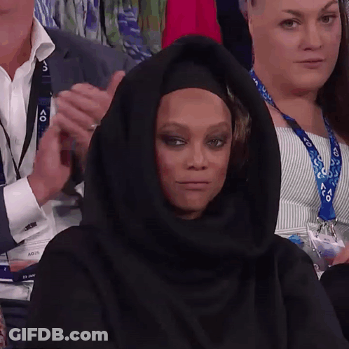 A Woman Wearing A Black Hijab Is Sitting In A Crowd Of People GIF