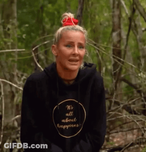 A Woman Wearing A Black Hoodie That Says `` It 'S All About Happiness '' Is Sitting In The Woods . GIF