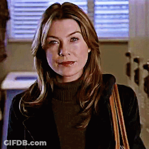 A Woman Wearing A Black Jacket And A Brown Purse Smiles GIF