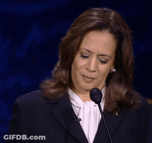 A Woman Wearing A Black Jacket And A White Shirt Stands In Front Of A Microphone Making A Funny Face GIF