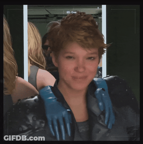 A Woman Wearing A Black Jacket And Blue Gloves Looks At The Camera With The Number 85 On The Screen GIF