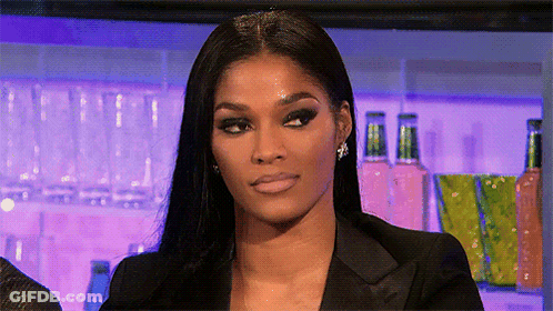 A Woman Wearing A Black Jacket And Earrings Is Making A Funny Face GIF