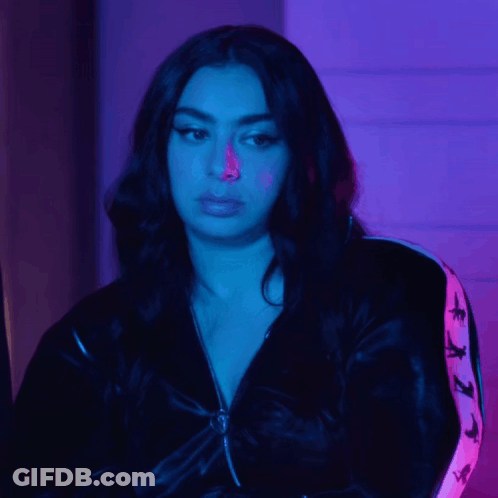 A Woman Wearing A Black Jacket With A Pink Stripe On The Sleeves Looks At The Camera GIF