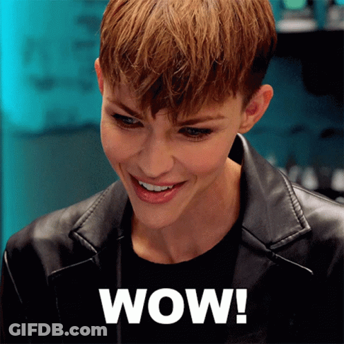 A Woman Wearing A Black Leather Jacket Is Smiling And The Word Wow Is On The Bottom Right GIF