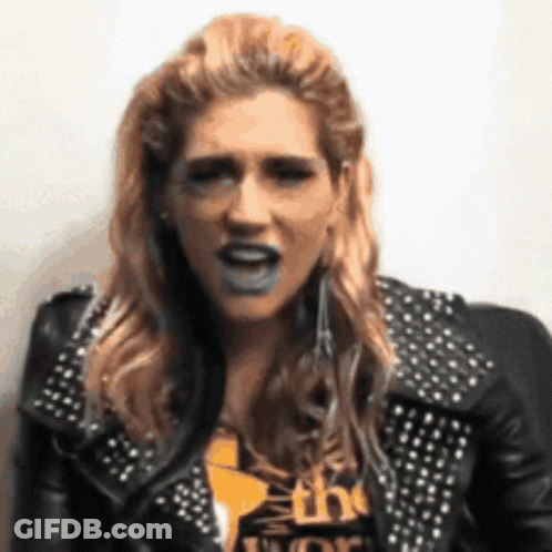 A Woman Wearing A Black Leather Jacket With Studs Is Making A Funny Face GIF