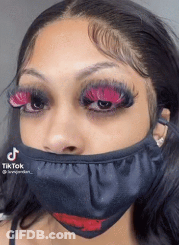 A Woman Wearing A Black Mask With A Red Lip On It . GIF
