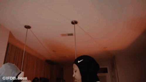 A Woman Wearing A Black Nike Headband Is Standing In A Dark Room . GIF