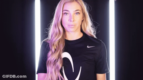 A Woman Wearing A Black Nike Shirt With A White Arrow On The Front GIF