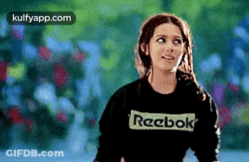 A Woman Wearing A Black Reebok Sweatshirt Is Looking Up . GIF