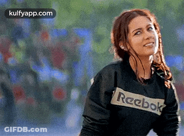 A Woman Wearing A Black Reebok Sweatshirt Is Smiling And Looking Up . GIF