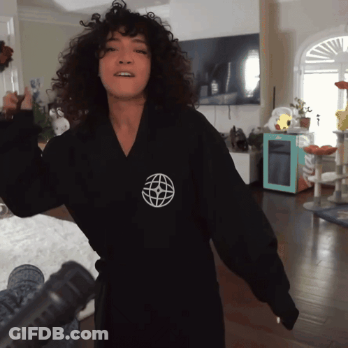 A Woman Wearing A Black Robe With A White Globe On The Front GIF