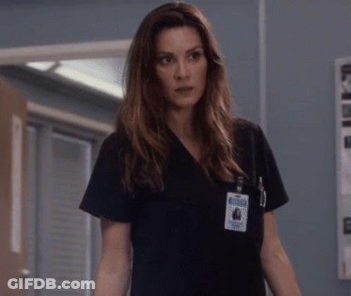 A Woman Wearing A Black Scrub Top Has A Name Tag On Her Chest That Says ' Nurse ' GIF
