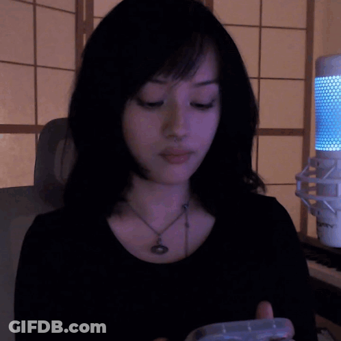A Woman Wearing A Black Shirt And A Necklace Is Sitting In Front Of A Microphone That Says ' Sven ' GIF