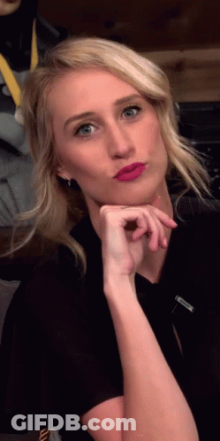 A Woman Wearing A Black Shirt And Pink Lipstick Is Making A Face GIF