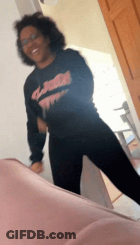 A Woman Wearing A Black Shirt That Says ' Jesus ' On It Is Dancing GIF