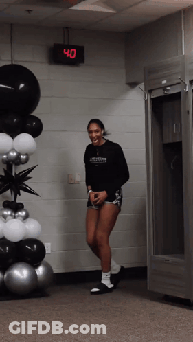 A Woman Wearing A Black Shirt That Says Las Vegas Basketball Is Standing In Front Of Balloons GIF