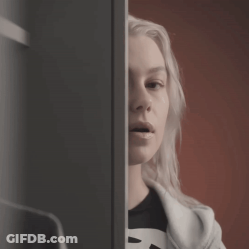 A Woman Wearing A Black Shirt With The Letter B On It Looks At Herself In The Mirror GIF