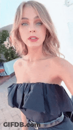 A Woman Wearing A Black Strapless Top Is Taking A Selfie With Her Eyes Closed GIF
