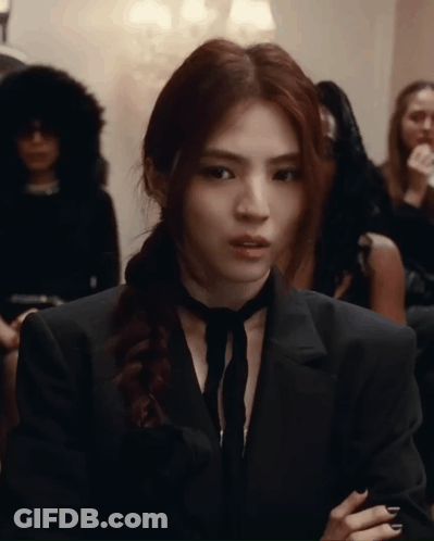 A Woman Wearing A Black Suit And Tie Is Looking At The Camera GIF