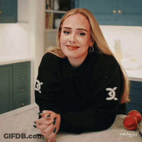 A Woman Wearing A Black Sweater With A White X On The Sleeve GIF