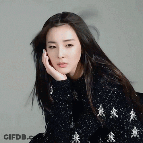 A Woman Wearing A Black Sweater With Silver Trees On It GIF