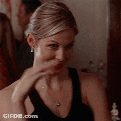 A Woman Wearing A Black Tank Top And A Necklace Is Making A Funny Face GIF