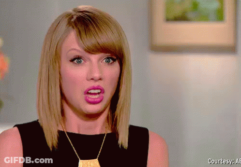 A Woman Wearing A Black Top And A Gold Necklace Is Making A Surprised Face GIF