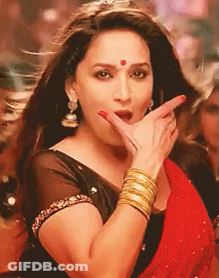 A Woman Wearing A Black Top And A Red Saree Is Making A Funny Face With Her Hand . GIF