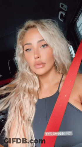 A Woman Wearing A Black Top And A Red Seat Belt Is Sitting In A Car In Nyc Diamond District GIF
