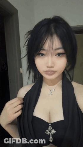 A Woman Wearing A Black Top With A Cross Necklace GIF