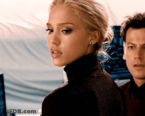 A Woman Wearing A Black Turtleneck Sweater And Earrings Stands Next To A Man GIF