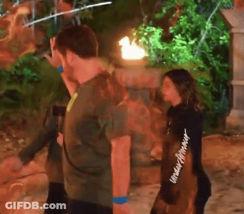 A Woman Wearing A Black Under Armour Sweatshirt Stands Next To A Man In A Green Shirt GIF
