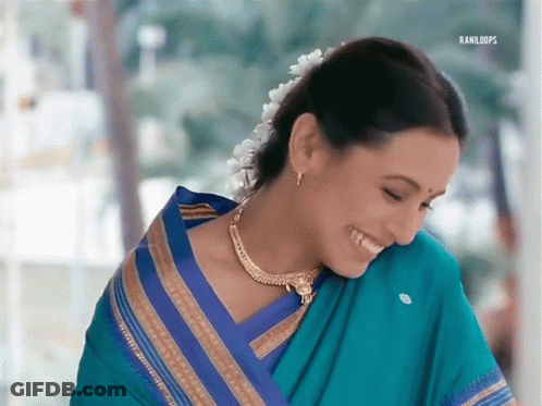 A Woman Wearing A Blue And Gold Striped Saree Is Smiling GIF