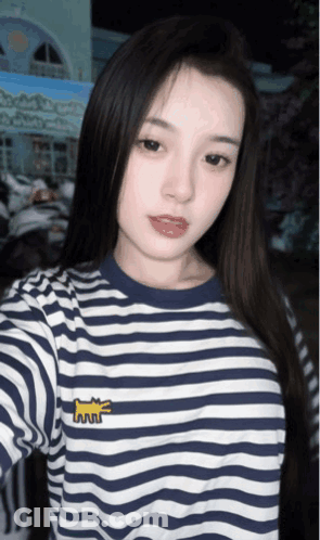 A Woman Wearing A Blue And White Striped Shirt Takes A Selfie With Her Phone GIF