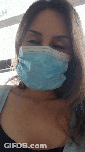 A Woman Wearing A Blue Face Mask With The Letter H On The Wall Behind Her GIF