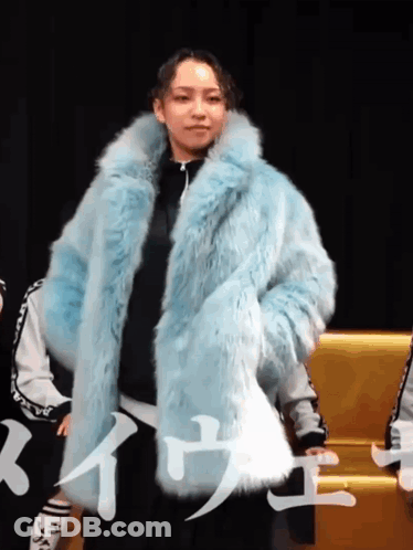 A Woman Wearing A Blue Fur Coat With Chinese Writing On The Bottom GIF