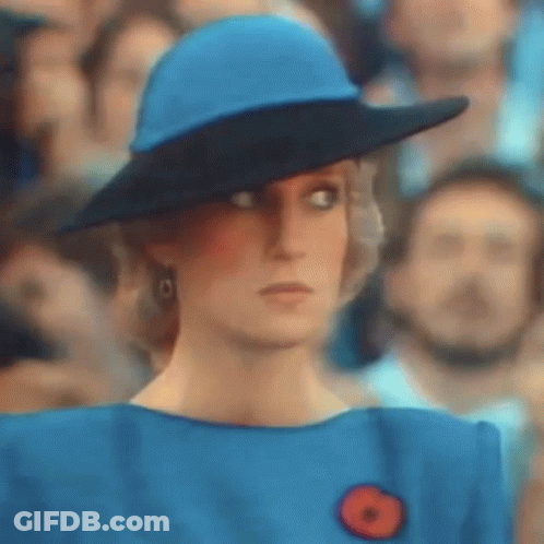 A Woman Wearing A Blue Hat And A Blue Dress Is Standing In Front Of A Crowd Of People . GIF