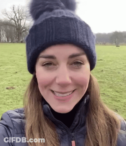 A Woman Wearing A Blue Hat And A Blue Jacket Is Smiling . GIF