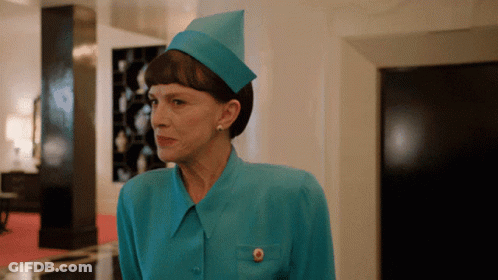 A Woman Wearing A Blue Hat And A Blue Shirt Has A Gold Button On Her Pocket GIF
