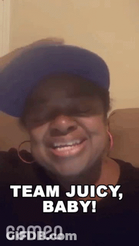 A Woman Wearing A Blue Hat And Earrings Is Smiling And Saying Team Juicy Baby . GIF
