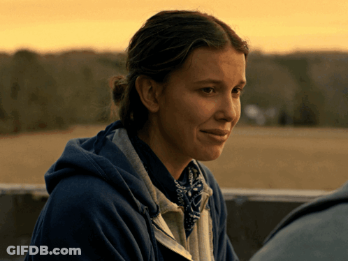 A Woman Wearing A Blue Hoodie And A Bandana Looks Down GIF
