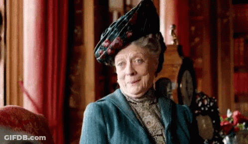 A Woman Wearing A Blue Jacket And A Hat Is Sitting In A Chair . GIF