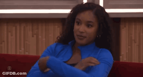 A Woman Wearing A Blue Jacket Sits On A Red Couch GIF
