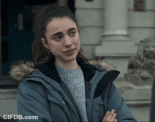 A Woman Wearing A Blue Jacket With A Fur Hood Is Standing In Front Of A Building GIF